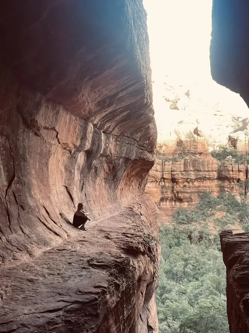 Hiker resting in a red rock alcove on Sedona's Broadway Trail