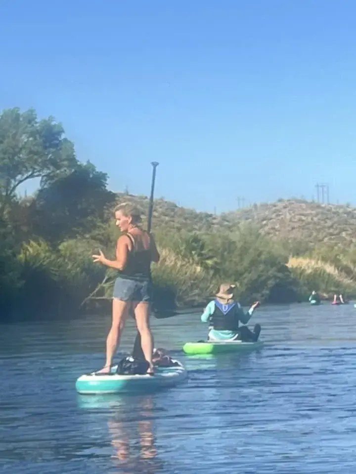 Two paddlers on the water, one standing, one kneeling